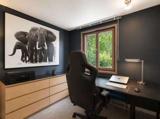 This modern home office features a striking black and white elephant artwork that adds a touch of drama to the dark grey walls.