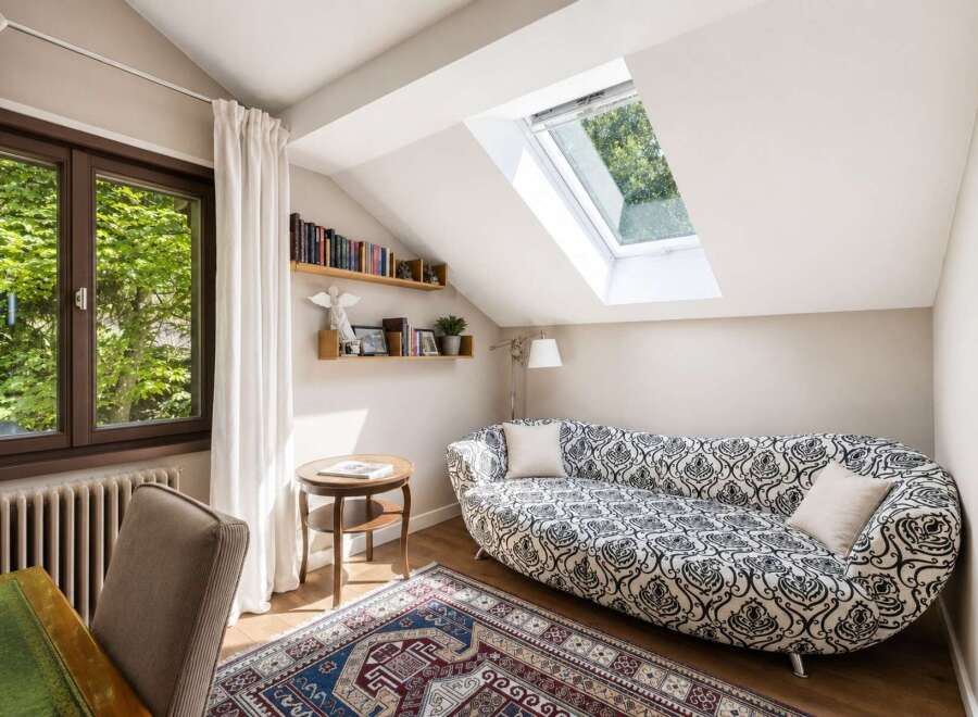 This charming attic room features a unique chaise lounge with a striking black and white pattern, perfect for relaxing.