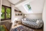 This charming attic room features a unique chaise lounge with a striking black and white pattern, perfect for relaxing.