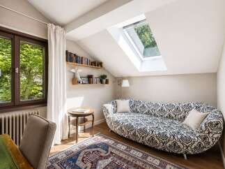 This charming attic room features a unique chaise lounge with a striking black and white pattern, perfect for relaxing.