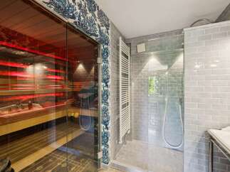 Experience ultimate relaxation in this luxurious bathroom featuring a modern sauna with vibrant red lighting and a spacious walk-in shower.