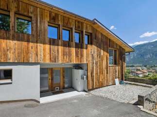 Discover this stunning modern home featuring a unique rustic wood exterior and large windows that flood the interior with natural light.