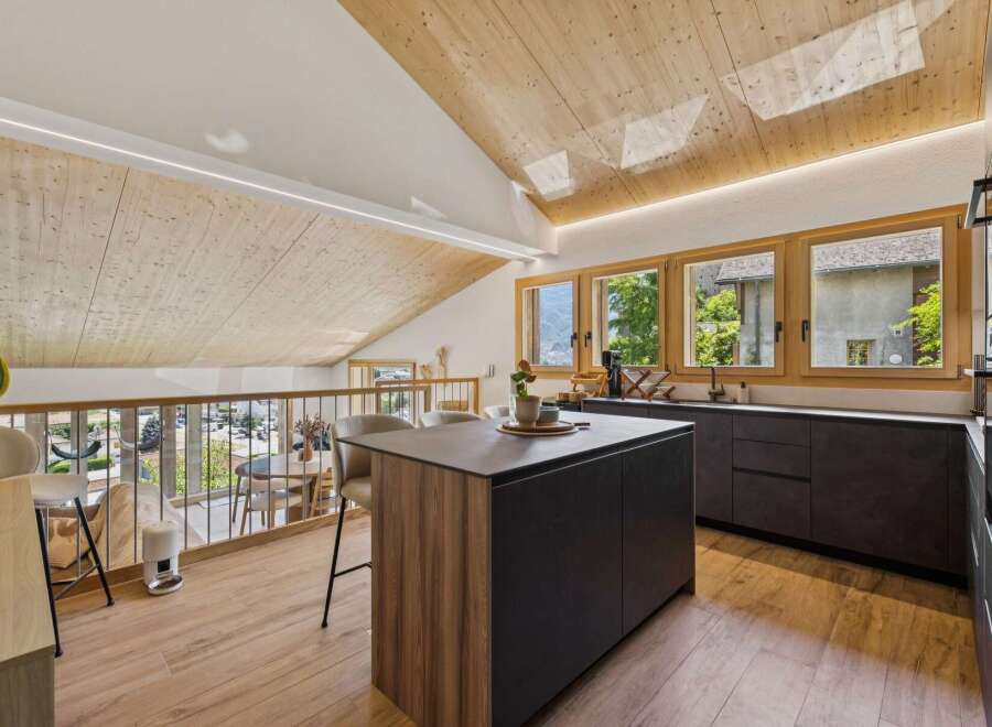 Experience modern living in this stunning attic kitchen, featuring a sleek island and ample counter space.