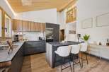 Experience modern living in this stunning kitchen featuring sleek, dark cabinetry complemented by warm wood accents on the upper cabinets and island.