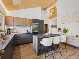 Experience modern living in this stunning kitchen featuring sleek, dark cabinetry complemented by warm wood accents on the upper cabinets and island.
