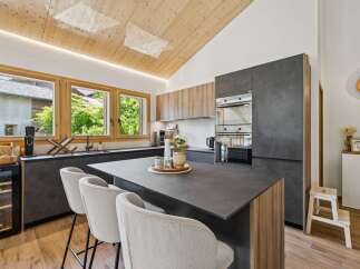 Experience modern living in this stunning kitchen featuring a sleek dark countertop island with comfortable bar seating.