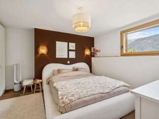 Experience serene mountain living in this charming bedroom, featuring a cozy bed with plush bedding and a unique heart-shaped headboard.