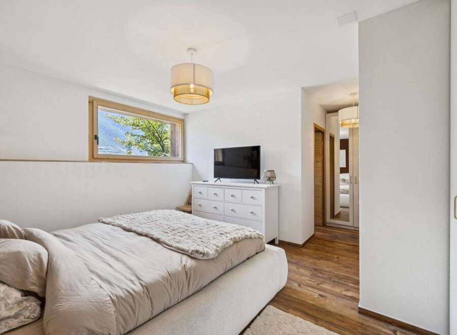 Experience serene mountain living in this charming bedroom, featuring a large horizontal window that frames breathtaking natural views.
