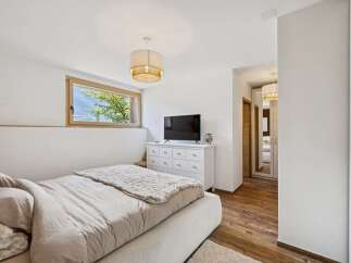 Experience serene mountain living in this charming bedroom, featuring a large horizontal window that frames breathtaking natural views.