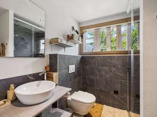 Experience modern comfort in this beautifully appointed bathroom, featuring a sleek vessel sink atop a stylish vanity.