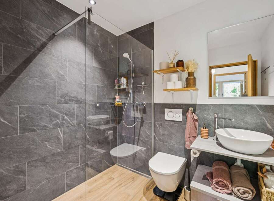 Experience modern luxury in this stunning bathroom featuring a spacious walk-in shower with elegant grey marble tiles and a sleek glass enclosure.