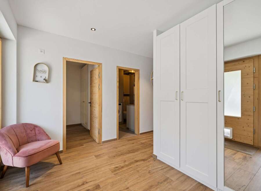 Step into this inviting entryway featuring a plush pink accent chair perfect for a moment of relaxation.