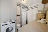 Discover this compact and functional utility room, featuring a modern Bosch washing machine and ample storage cabinets.