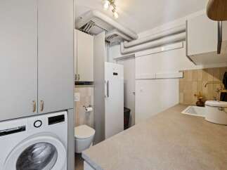 Discover this compact and functional utility room, featuring a modern Bosch washing machine and ample storage cabinets.