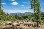 Experience the ultimate mountain getaway with this rustic campsite, featuring log benches and a fire pit perfect for gathering.