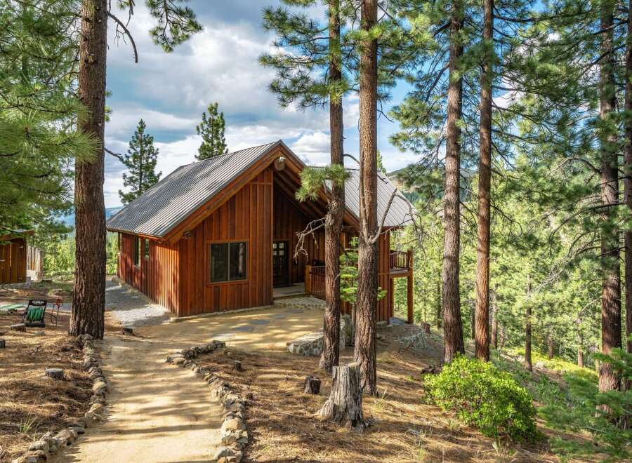 Nestled amidst towering pine trees, this charming wooden cabin offers a serene mountain retreat.