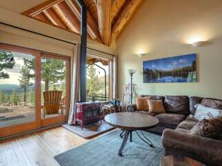 Experience rustic charm in this cozy living room featuring a striking red wood-burning stove and expansive sliding glass doors that open to breathtaking mountain views.