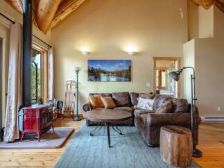 Experience rustic charm in this cozy living room, featuring a striking red wood-burning stove and exposed wooden beams that add warmth and character.