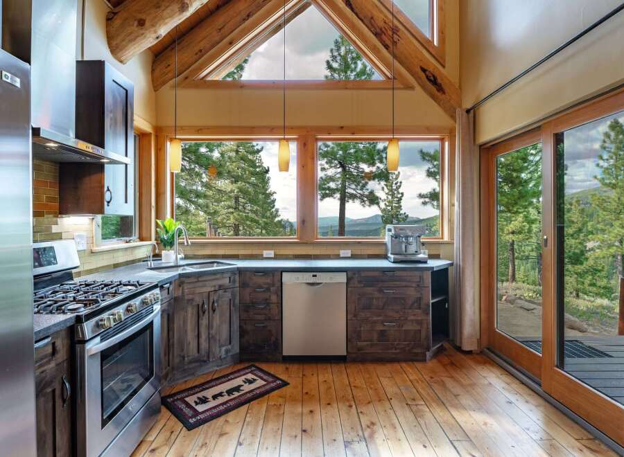 Experience breathtaking mountain views from this stunning kitchen, featuring rustic wood cabinetry and a sleek stainless steel appliance suite.