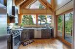 Experience breathtaking mountain views from this stunning kitchen, featuring rustic wood cabinetry and a sleek stainless steel appliance suite.