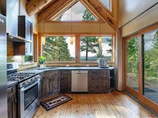 Experience breathtaking mountain views from this stunning kitchen, featuring rustic wood cabinetry and a sleek stainless steel appliance suite.