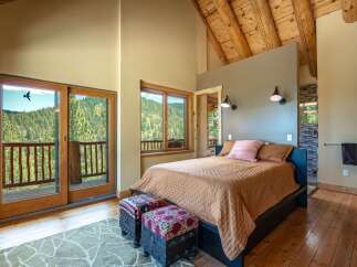 Experience breathtaking mountain views from this stunning bedroom, featuring a private balcony accessed through large sliding glass doors.