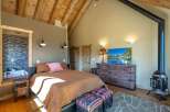 Experience rustic charm in this unique bedroom featuring a vaulted wood-beamed ceiling and a cozy wood-burning stove.