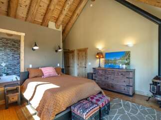 Experience rustic charm in this unique bedroom featuring a vaulted wood-beamed ceiling and a cozy wood-burning stove.
