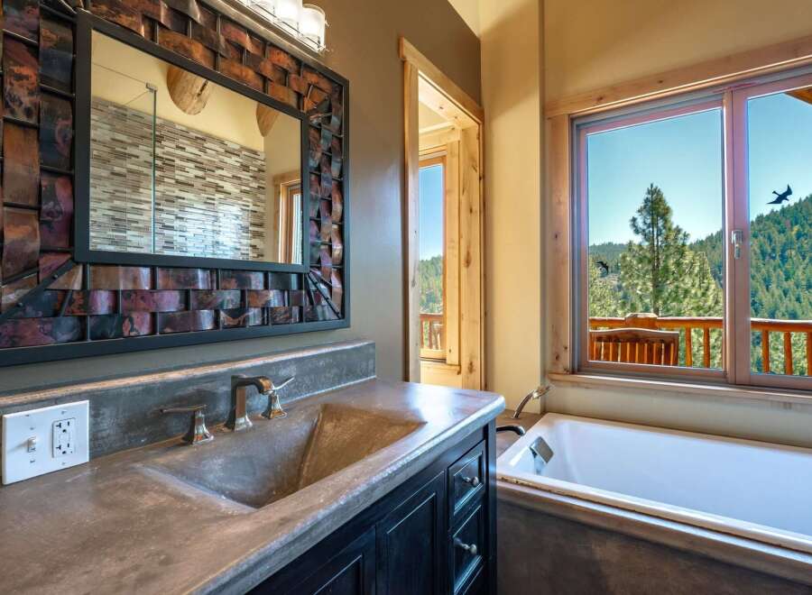 Experience luxury mountain living with this stunning bathroom featuring a concrete vanity and a deep soaking tub.