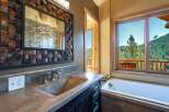 Experience luxury mountain living with this stunning bathroom featuring a concrete vanity and a deep soaking tub.