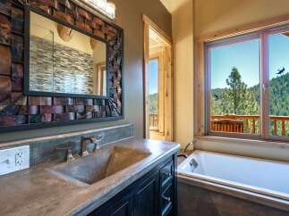 Experience luxury mountain living with this stunning bathroom featuring a concrete vanity and a deep soaking tub.