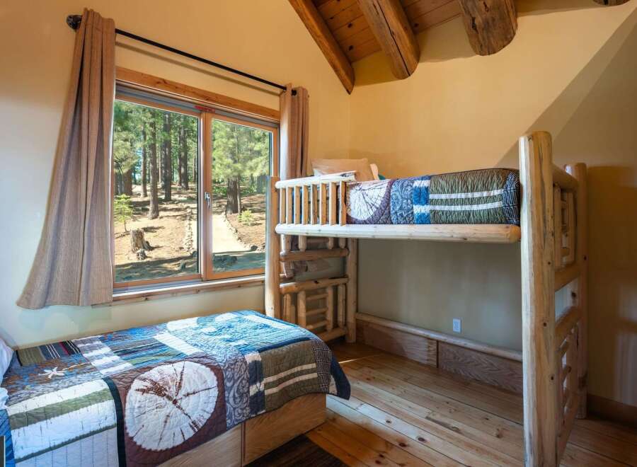 Experience rustic charm in this cozy cabin bedroom featuring a comfortable twin bed and a space-saving bunk bed, perfect for families or guests.