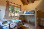 Experience rustic charm in this cozy cabin bedroom featuring a comfortable twin bed and a space-saving bunk bed, perfect for families or guests.
