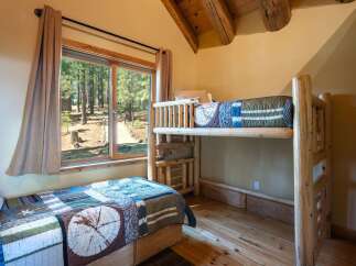 Experience rustic charm in this cozy cabin bedroom featuring a comfortable twin bed and a space-saving bunk bed, perfect for families or guests.