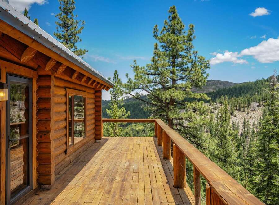 Experience breathtaking mountain views from the expansive wooden deck of this charming log cabin.
