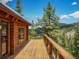 Experience breathtaking mountain views from the expansive wooden deck of this charming log cabin.