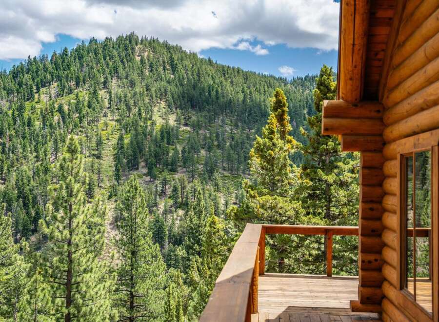 Experience breathtaking mountain views from the expansive wooden deck of this charming log cabin.