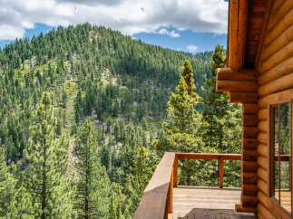 Experience breathtaking mountain views from the expansive wooden deck of this charming log cabin.