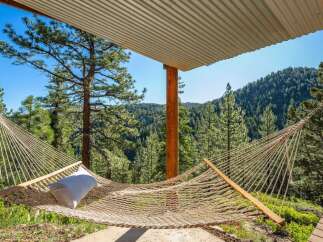 Relax and unwind in this serene mountain retreat, featuring a comfortable hammock perfect for enjoying the breathtaking forest views.