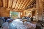 Experience rustic charm in this stunning log cabin living room, featuring a vaulted wood-beamed ceiling and a large picture window with breathtaking mountain views.