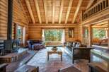 Experience rustic charm in this stunning log cabin living room, featuring a grand stone fireplace and exposed wooden beams.