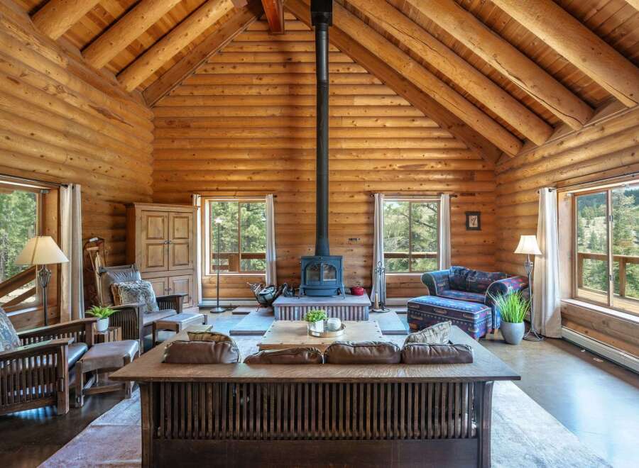 Experience rustic charm in this stunning log cabin living room, featuring a grand stone fireplace as the centerpiece.