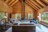 Experience rustic charm in this stunning log cabin living room, featuring a grand stone fireplace as the centerpiece.