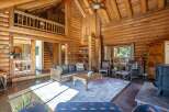 Experience rustic charm in this stunning log cabin living room, featuring a grand stone fireplace and soaring vaulted ceilings with exposed beams.