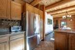 Experience rustic charm in this log cabin kitchen featuring a spacious stainless steel refrigerator and ample wooden cabinetry.