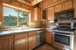 Experience rustic charm in this cozy log cabin kitchen, featuring beautiful natural wood cabinetry and a stunning stained-glass accent cabinet.
