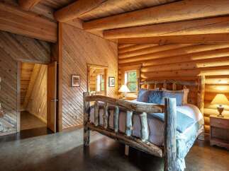 Experience rustic charm in this cozy log cabin bedroom, featuring a handcrafted log bed and warm wood accents throughout.