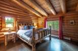 Experience rustic charm in this cozy log cabin bedroom, featuring a unique log bed frame and warm wood interiors.
