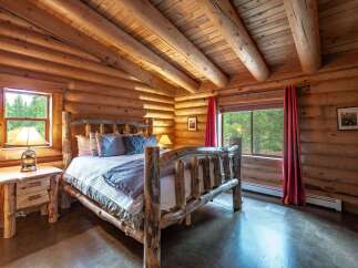 Experience rustic charm in this cozy log cabin bedroom, featuring a unique log bed frame and warm wood interiors.