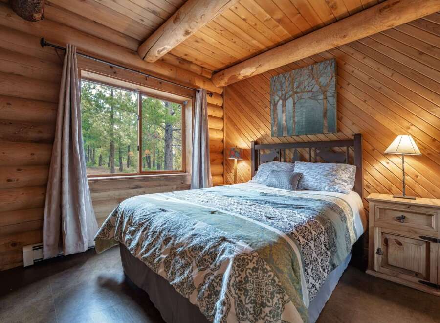 Experience rustic charm in this cozy log cabin bedroom, featuring a comfortable queen-size bed adorned with a nature-inspired comforter.